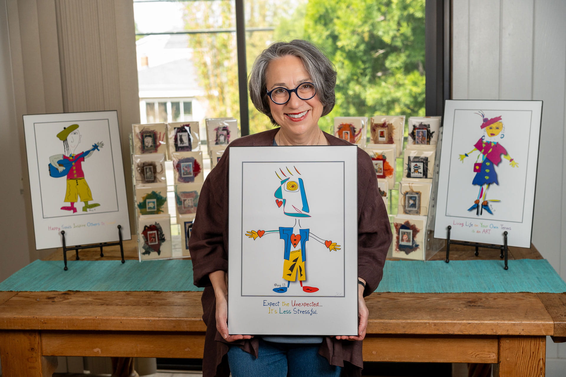 Elisa Goodman, owner and designer of Curmudgeon Cards, holding her "Peakasso" poster